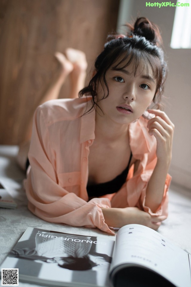 A woman laying on the floor next to a book.