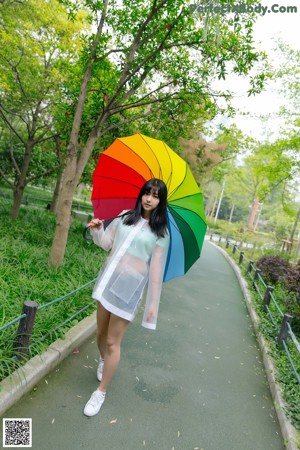 A woman in a white dress holding a colorful umbrella.