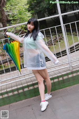 A woman in a white dress holding a colorful umbrella.