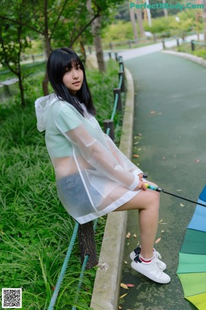 A woman in a white shirt and blue shorts holding an umbrella.