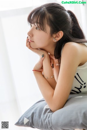 A woman sitting on top of a couch next to a window.