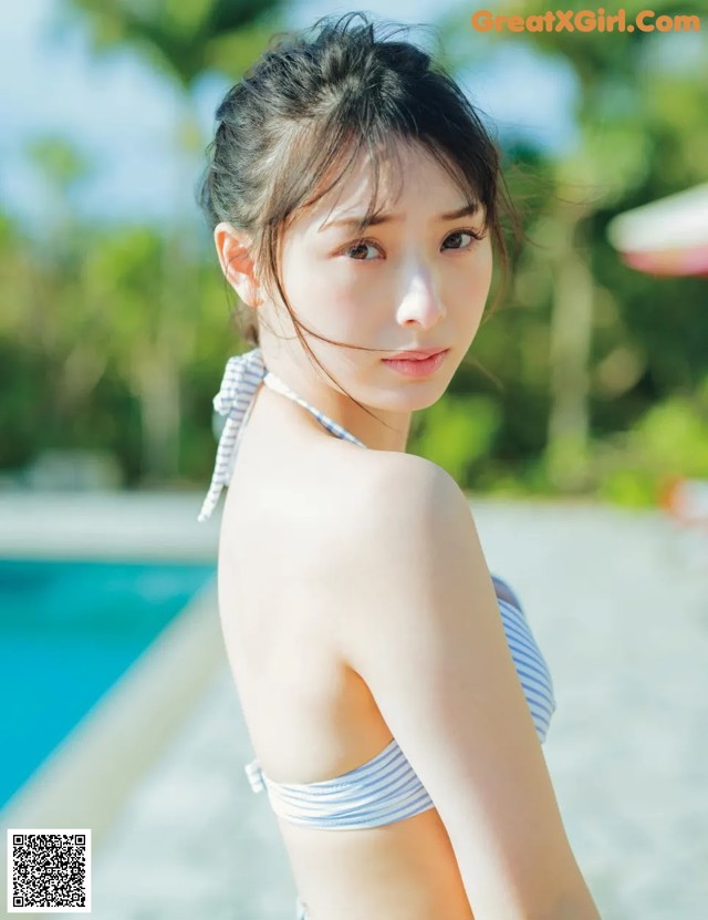 A woman in a bikini standing next to a swimming pool.