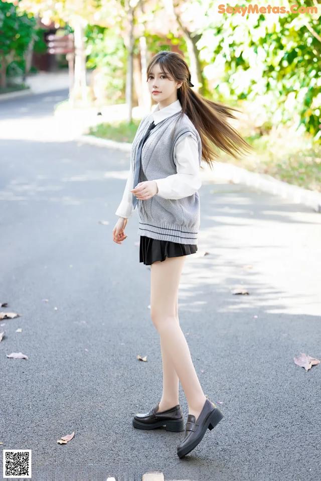 A young woman in a school uniform is walking down the street.