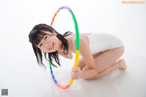 A woman in a white bathing suit sitting on the floor.