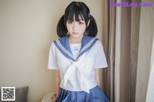A woman in a sailor outfit is tied up on a couch.