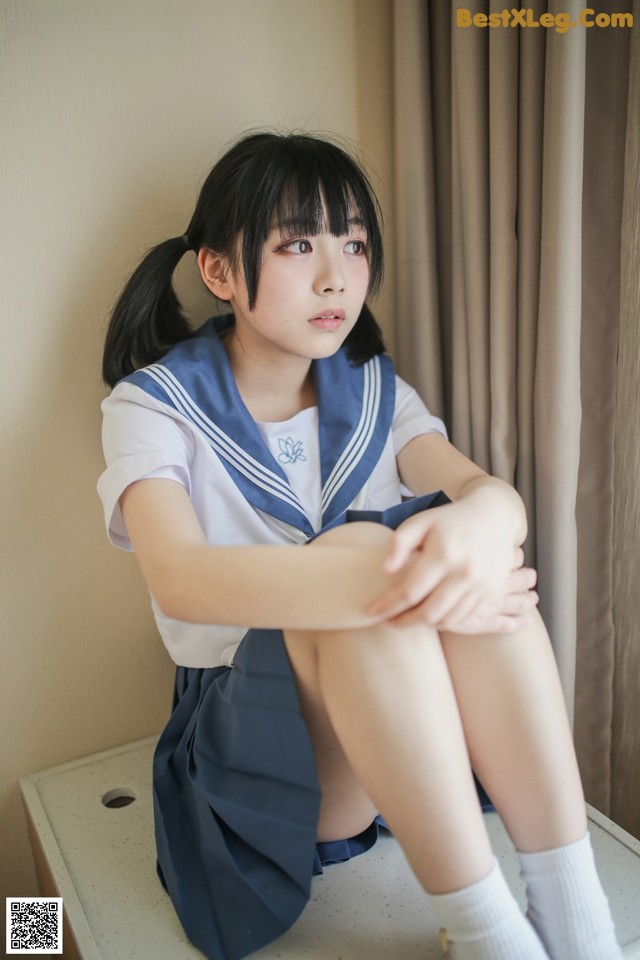 A woman in a school uniform sitting on a table.