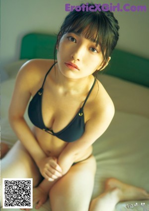A woman in a bikini laying on a bed.