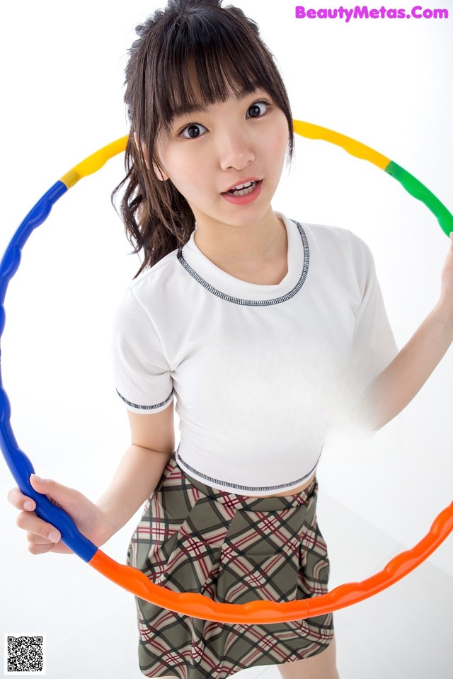 A young woman holding a hula hoop in her hands.