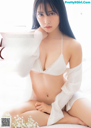 A woman in a white bikini posing on a bed.
