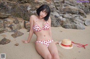 A woman in a straw hat sitting on a rock.