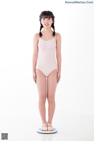 A young girl in a pink leotard and pointe shoes.