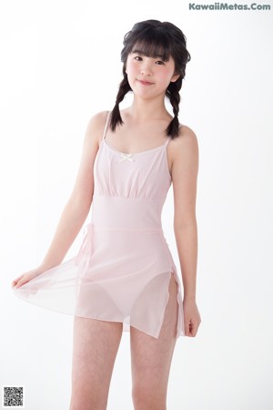 A young girl in a pink leotard leaning against a wall.