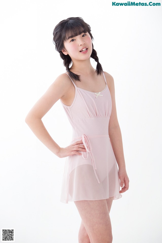 A young woman in a pink dress posing for a picture.