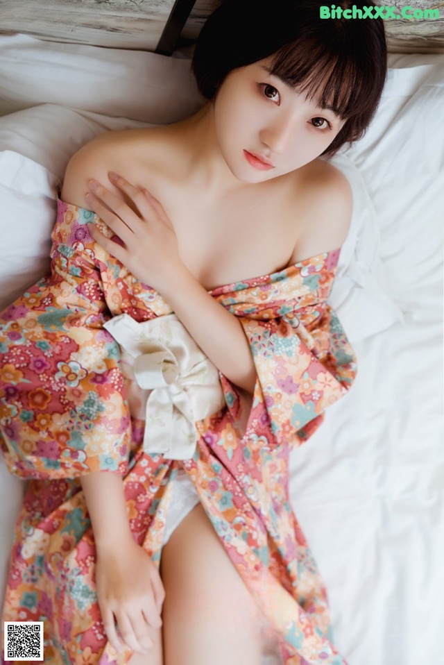 A woman in a kimono laying on a bed.