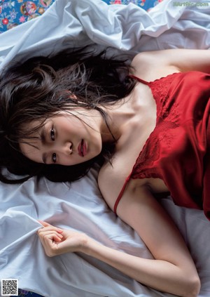 A woman in a red dress sitting on a bed.