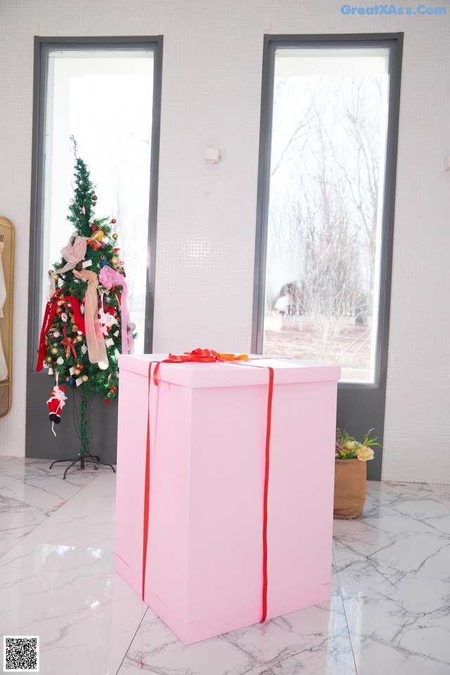 A large pink box with a red ribbon tied around it.