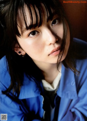 A woman in a blue jacket sitting on a green boat.