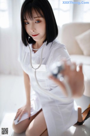 A woman in a white shirt and black high heels leaning against a white couch.