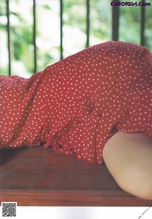 A woman sitting on the ground under an umbrella.