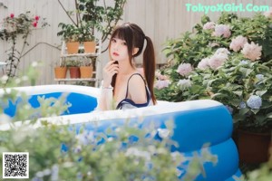 A woman in a bikini sitting in an inflatable pool.