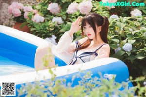 A woman in a white and blue lingerie posing by a pool.