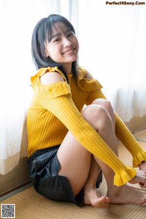 A woman in a white shirt and plaid skirt posing for a picture.