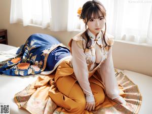A woman in an orange kimono posing for the camera.
