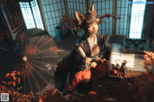 A woman in a black and red kimono sitting on a bed with an umbrella.