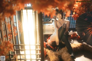 A woman in a kimono sitting on a chair holding an umbrella.
