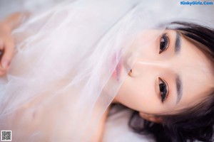 A woman in a white lingerie sitting on a bed.