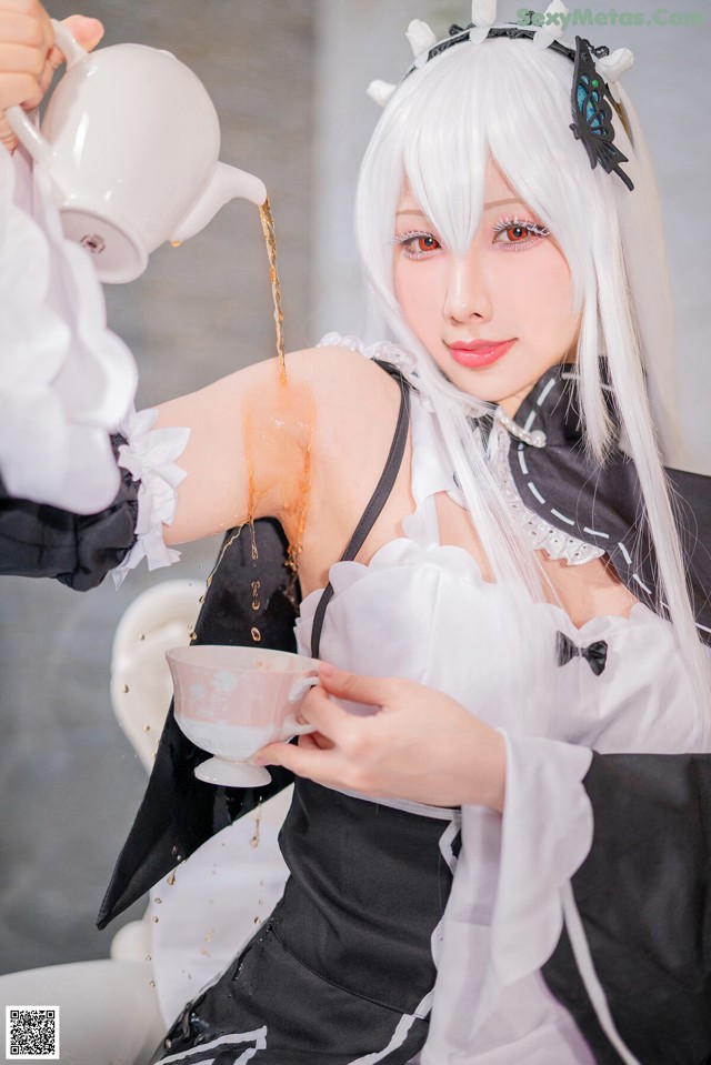 A woman in a maid outfit pouring tea into a cup.