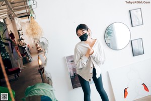 A woman standing in front of a mirror wearing a white sweatshirt and black pants.