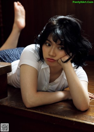 A woman in a red bathing suit sitting on a wooden bench.