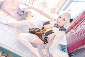 A woman in a maid outfit sitting on a chair.