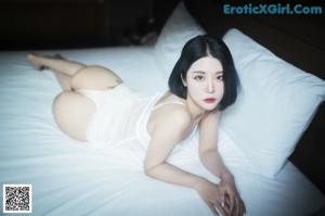 A woman laying on a bed in a white bra and panties.