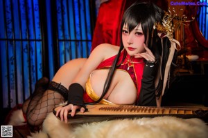 A woman in a red and black outfit sitting on a bed.