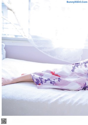 A woman in a kimono laying on a bed.