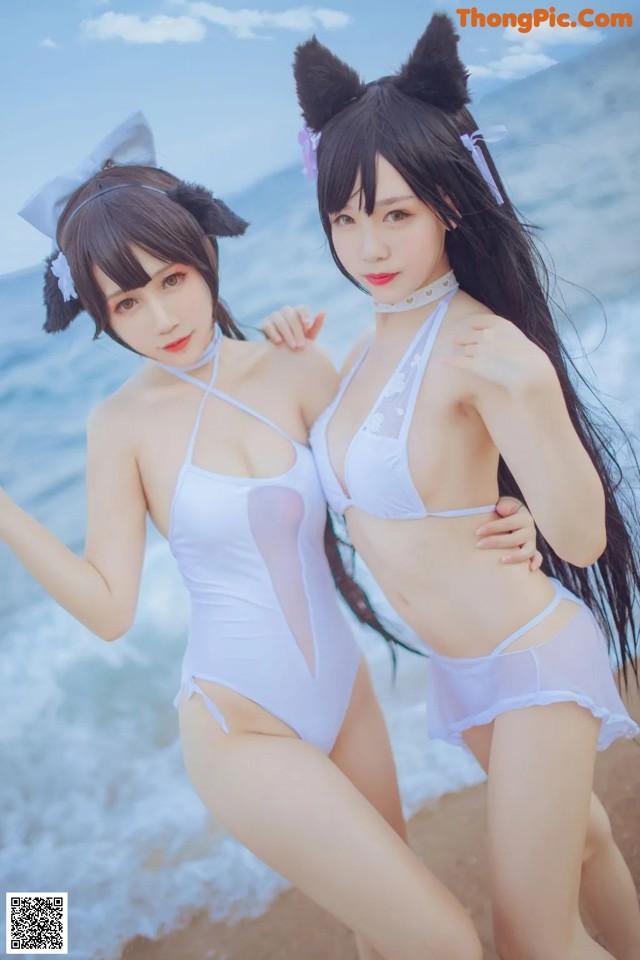 Two women in bunny ears are posing on the beach.