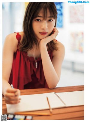 A woman in a red dress standing in front of a poster.