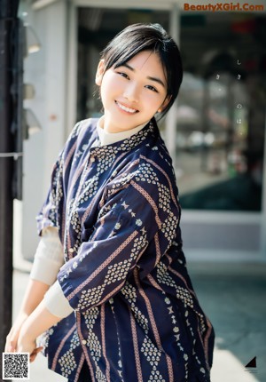 A woman in a blue kimono standing next to a body of water.