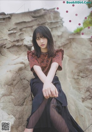 A woman leaning against a wooden post on the beach.