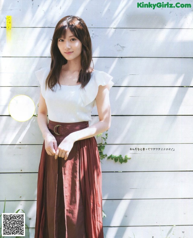 A woman standing in front of a white wall.