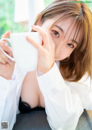 A woman in a lab coat is putting something in a microwave.